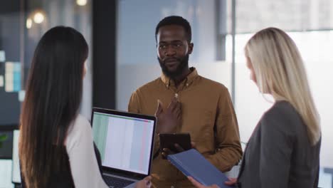 Group-of-diverse-businesspeople-discussing-together-and-using-laptop