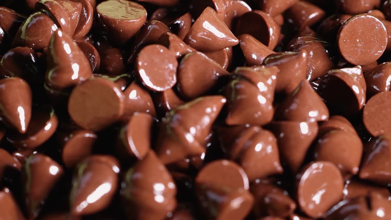 A detailed view of glossy chocolate chips clustered closely, highlighting their rich texture and shine.