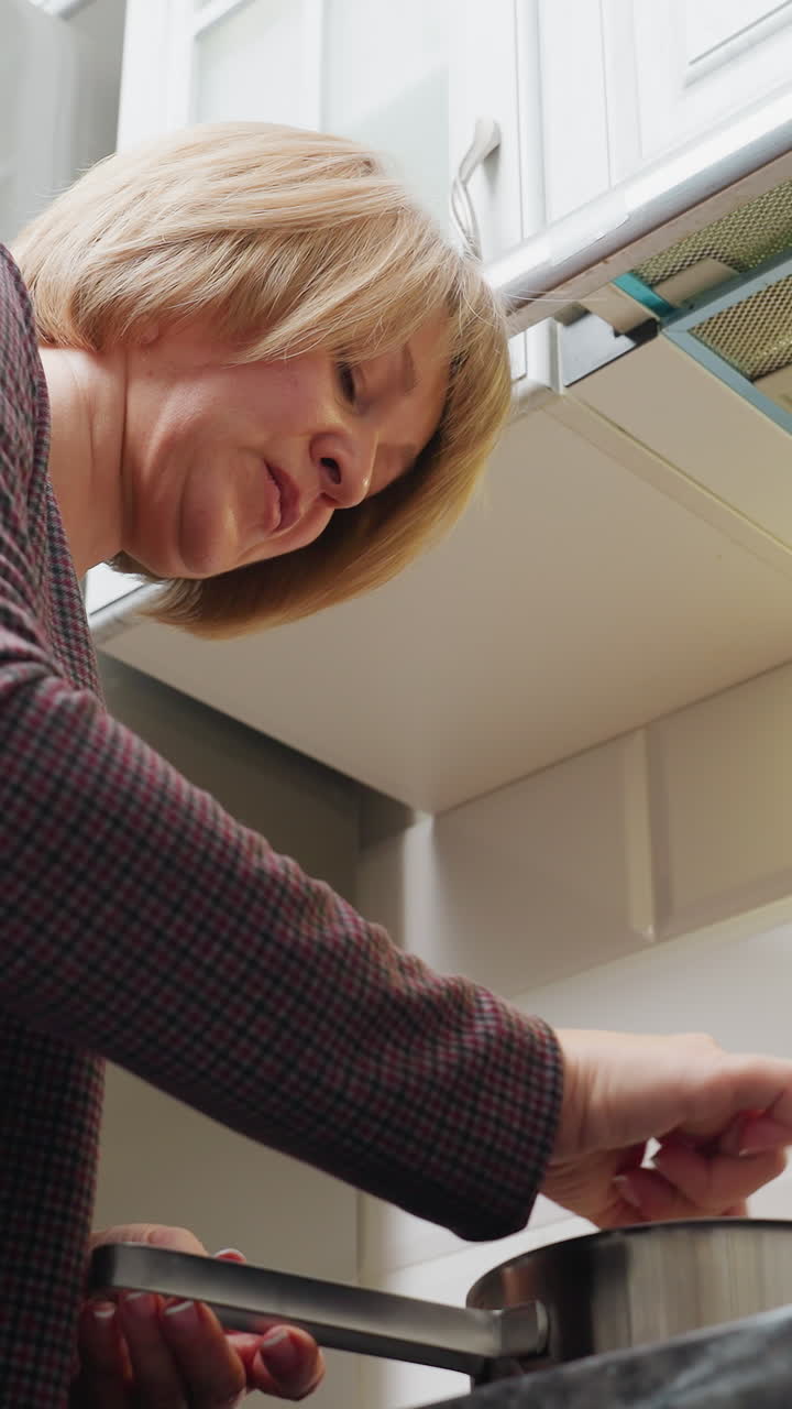 아름다운 현대 주방에서 요리하는 여성의 상단 각도 뷰, 비에 재료를 고, 체크 된 셔츠를 입고, 요리를 즐기고, 배경에 보이는 주방 장비