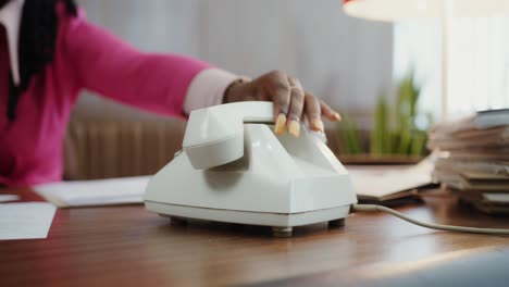 secretary is answering the phone in the office at work, old analog land line phone technology