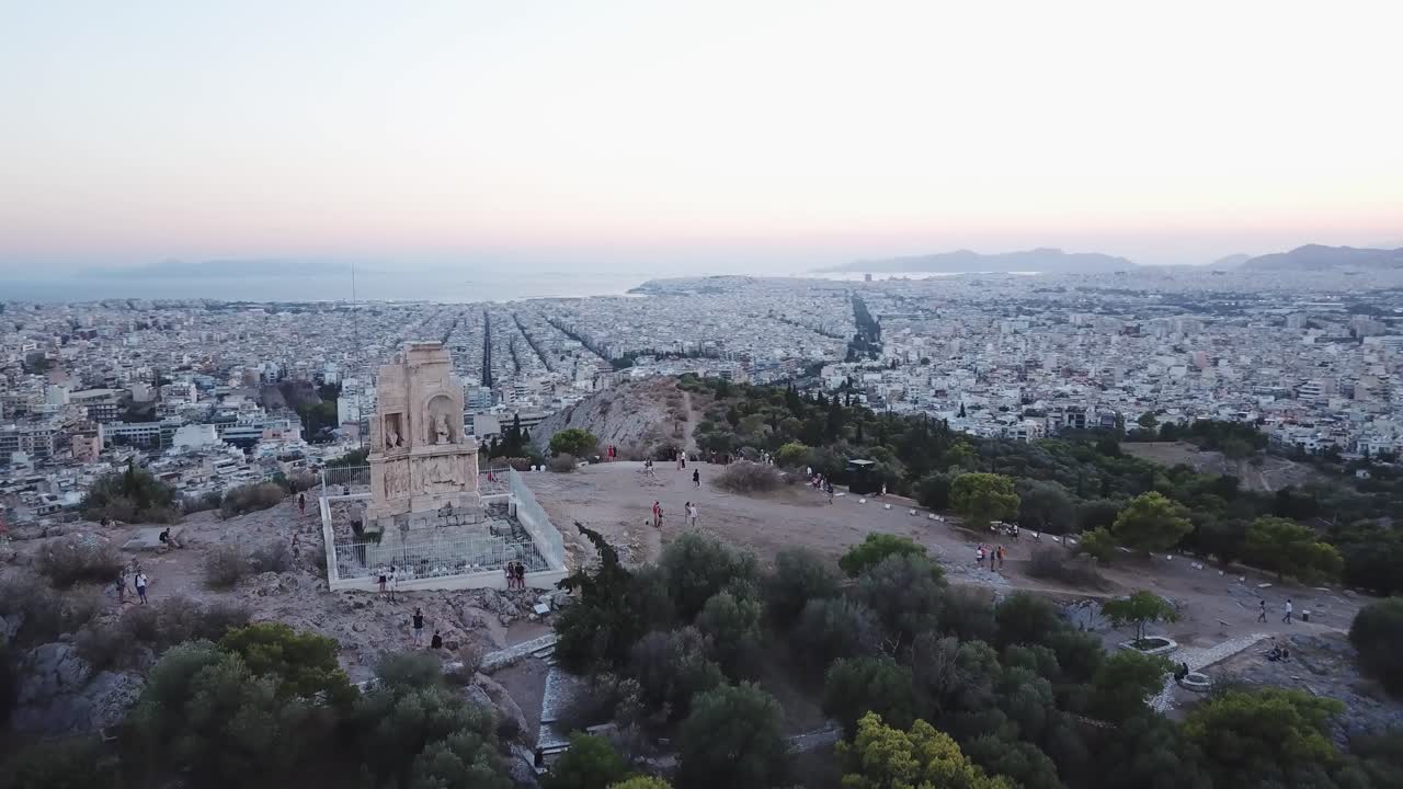 People watching sunset on top of a hill over Athens at Monument of Philopappos
