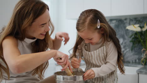 adorable child helping mom kitchen closeup. positive family having fun cooking