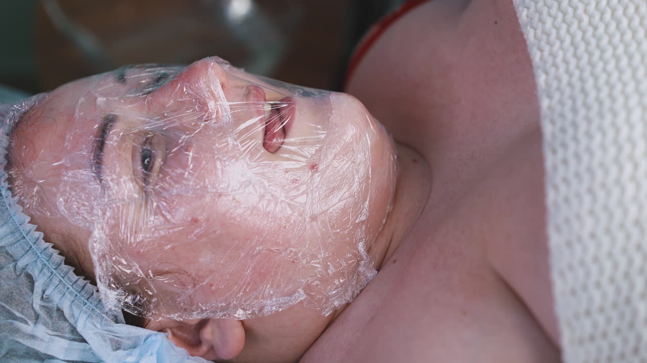 una grande donna con una maschera di foglio tocca la plastica con la lingua