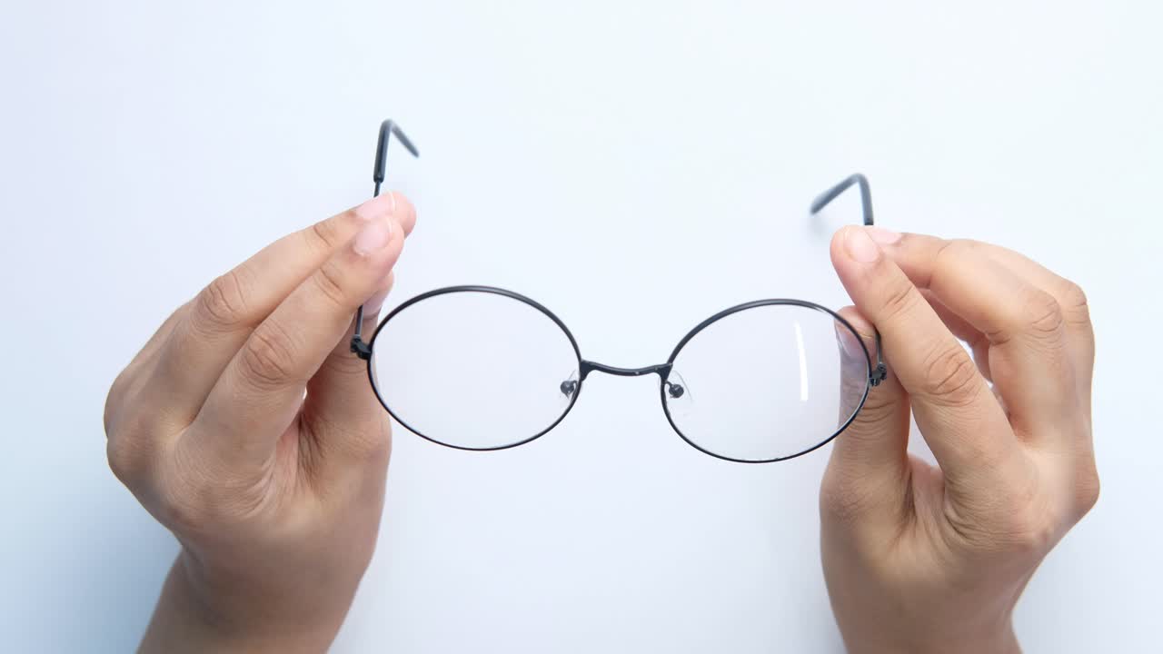 manos con gafas negras redondas