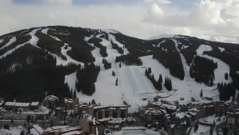 Aerial-Drone-Copper-Mountain-Colorado-Ikon-Epic-Pass-winter-spring-cloudy-snowy-afternoon-sunset-last-light-half-pipe-chairlift-ski-runs-center-village-cinematic-slowly-forward-reveal-motion