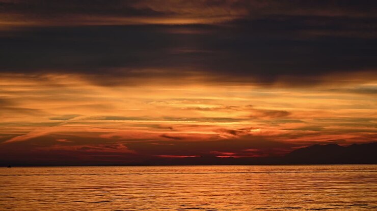 Sunset on the Aegean sea. Yellow illumination, land in the distance, water, Greece