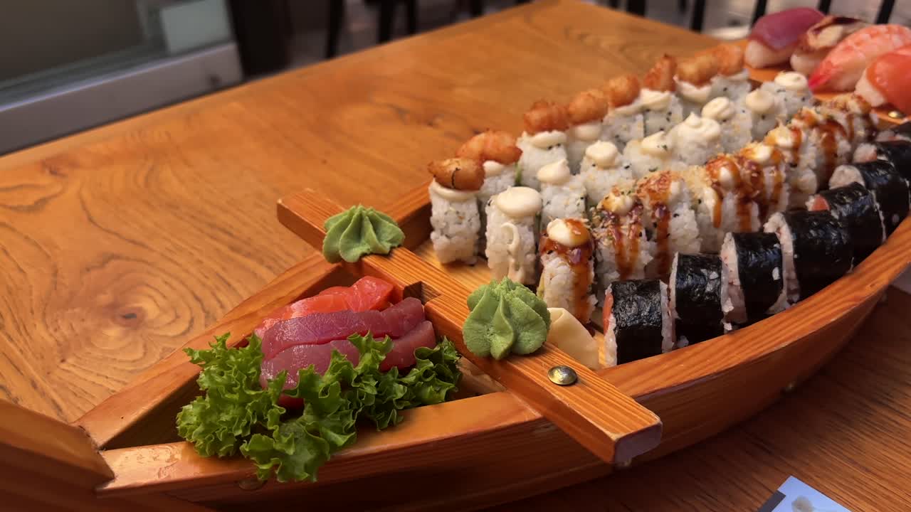 Wooden sushi boat platter with assorted sushi rolls and sashimi