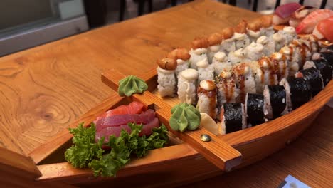 wooden sushi boat platter with assorted sushi rolls and sashimi