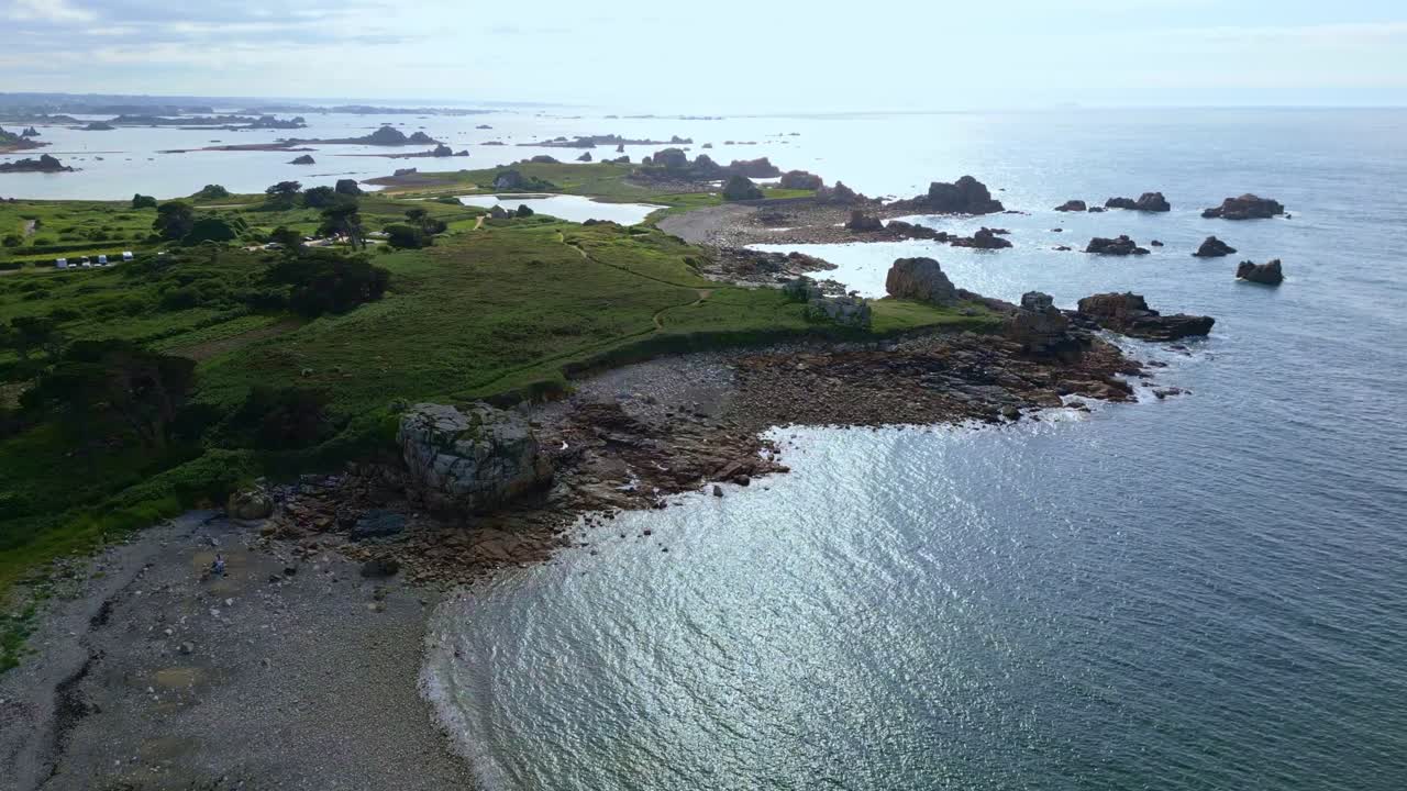 Drone flight toward Shark Head Rock on Brittany’s Pink Granite Coast with calm sea and nearby beach - France