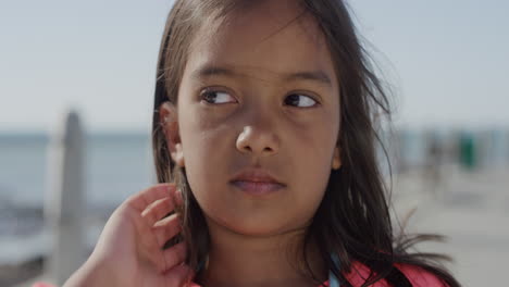 Nahaufnahme-Eines-Porträts-Eines-Jungen-Mädchens-Mit-Gemischter-Rasse,-Das-Ernst-Aussieht-Und-Mit-Der-Hand-Durch-Die-Haare-Am-Windigen-Strand-In-Zeitlupe-Rennt