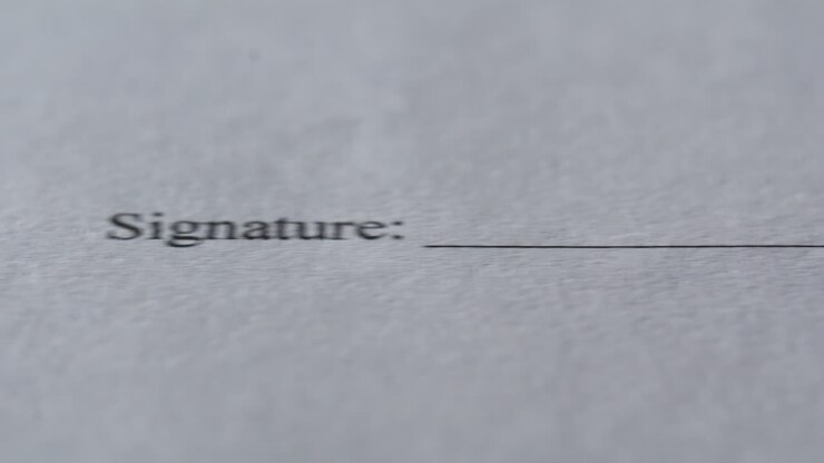 Modulo legale in primo piano appoggiato sul bancone del posto di lavoro. Documenti disposti per la firma.