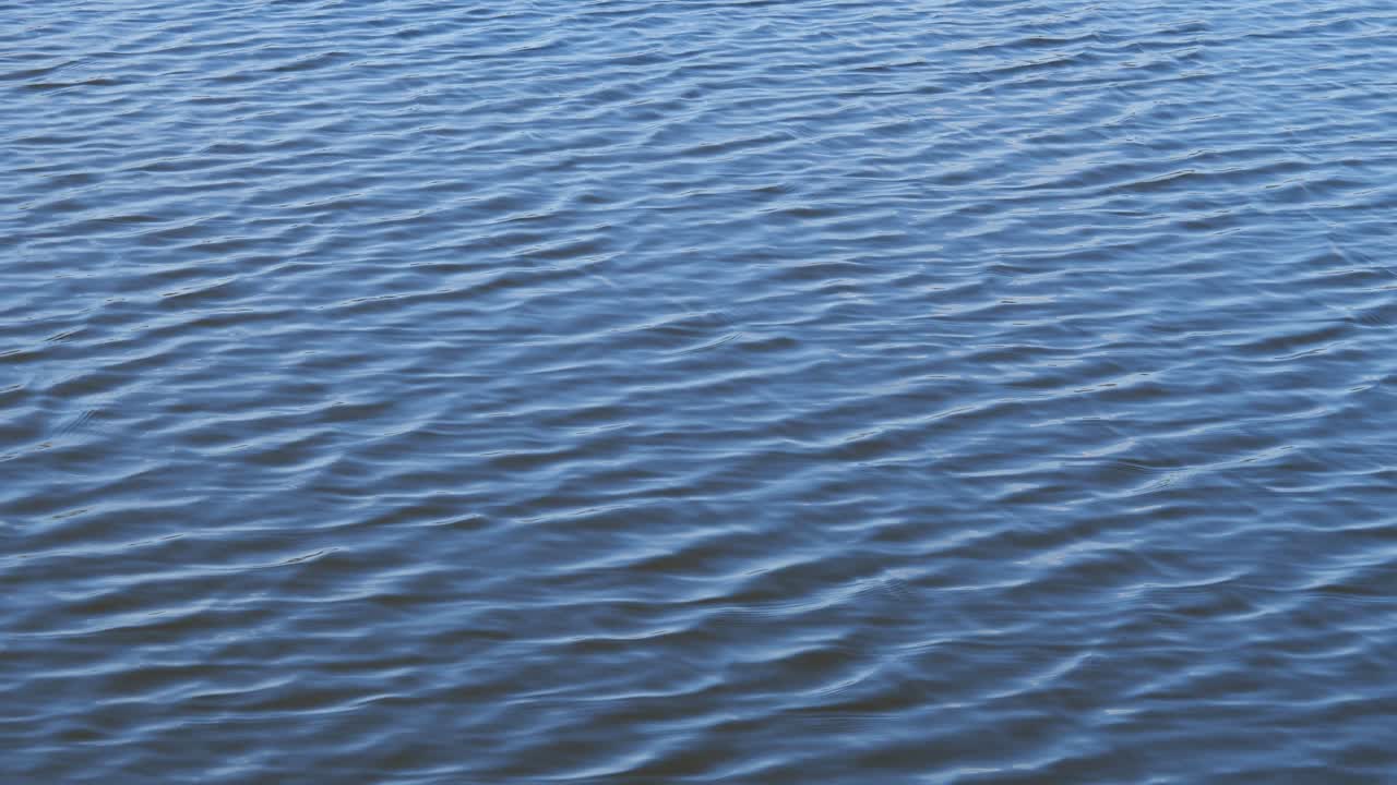 Superficie de agua abstracta con pequeñas olas y reflejo del cielo