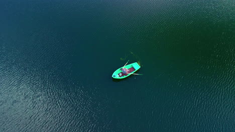 a person fishing from a rowboat on a huge lake - pullback aerial