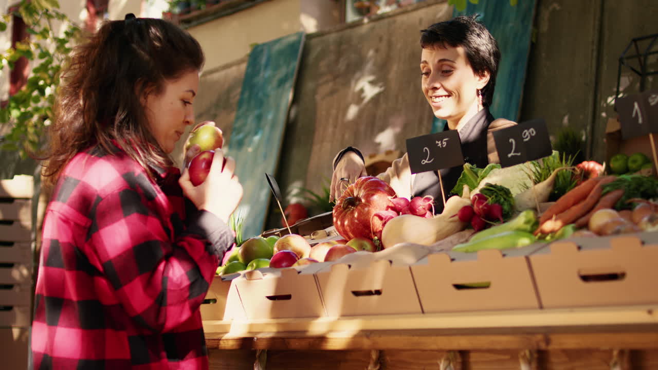 People buying and selling fruits and vegetables at an outdoor market stall