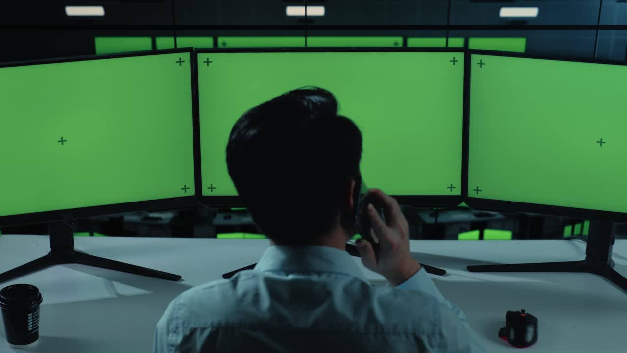 사무실 에서 여러 컴퓨터 모니터 를 모방 하여 작업 하는 동안 휴대 전화 로 대화 하는 아시아인 의 뒷면