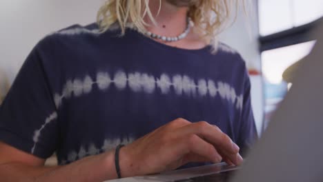 Caucasian-male-surfboard-maker-working-on-a-project-using-his-laptop