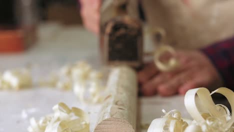 A-macro-shot-of-a-Carpenter-using-an-antique-traditional-plane-on-a-piece-of-wood-in-slow-motion-with-a-rack-focus