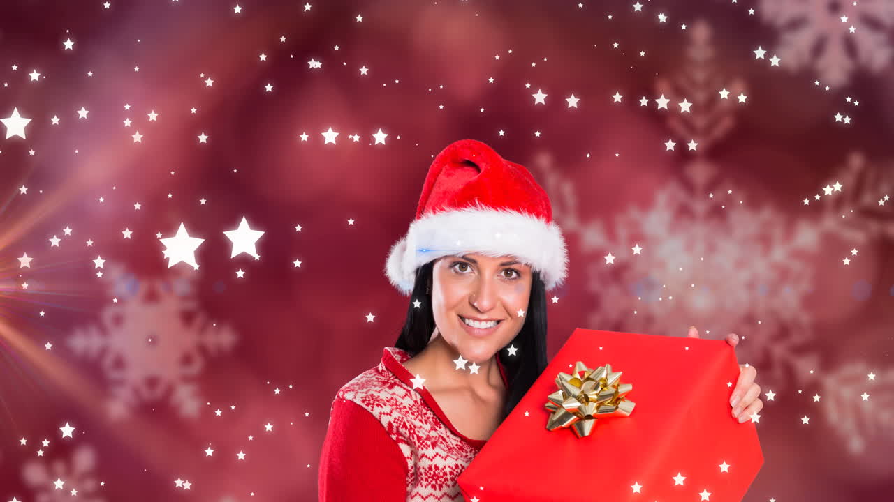 animación de estrellas cayendo sobre feliz mujer caucásica con sombrero de santa manteniendo presente