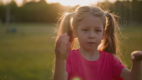 tired little girl waves to cool down in park at sunset