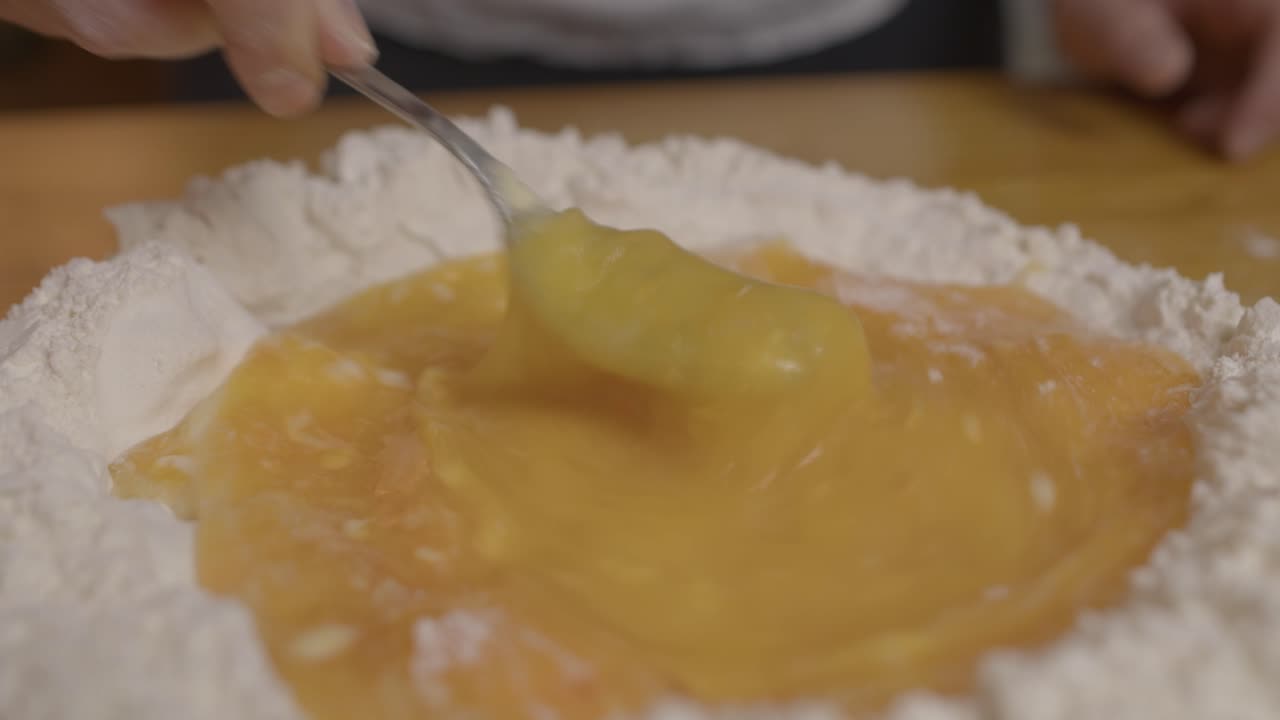 chef mezclando yemas de huevo con la masa de pasta con tenedor