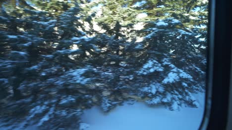 Traveling-by-train,-viewing-snowy-trees,-buildings,-and-cars-passing-by-through-the-window