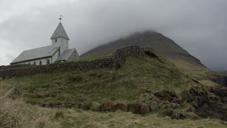 amplia inclinación hacia abajo de una iglesia y montañas en vidareidi, islas feroe