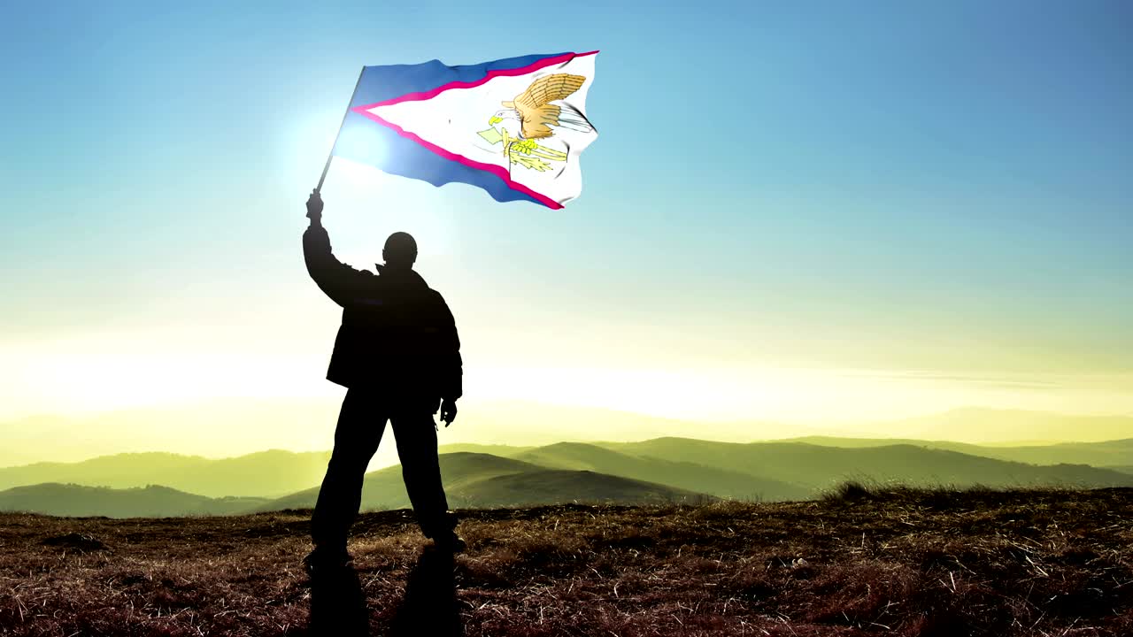 Uomo vincitore in silhouette di successo che sventola la bandiera delle Samoa Americane in cima alla vetta della montagna. Sfondo Cinemagraph LOOP.