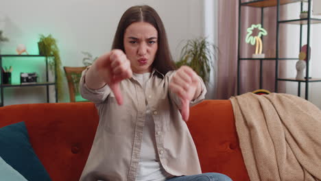 upset young woman showing thumbs down dislike bad work disapproval dissatisfied feedback at home