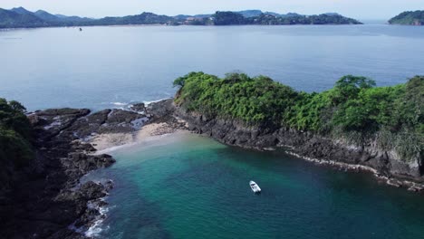 Small-islands-with-a-small-beach-and-a-small-anchored-boat-nearby