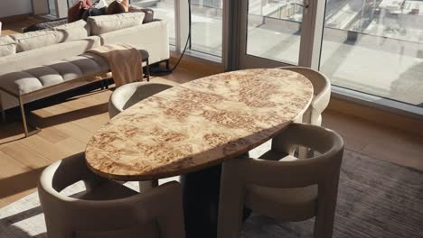 a modern and luxurious wooden table in a high rise condo next to large windows letting in natural sunlight