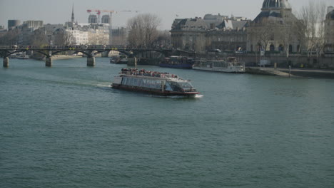 Bateaux-mouches-on-the-river-seine-with-tourists-in-Parisian-skyline,-slow-motion
