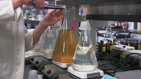 scientist in lab coat mixing chemicals in a glass bottle in a lab