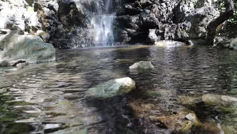 kalidonia waterfalls in troodos, cyprus—filmed from the bottom, surrounded by rocks and greenery. a popular hiking and tourist spot offering natural beauty and cool mountain vibes.