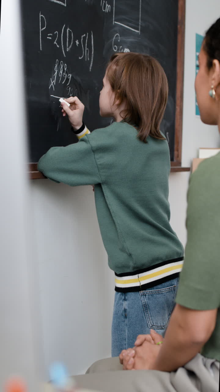 Student learning math on a chalkboard with teacher