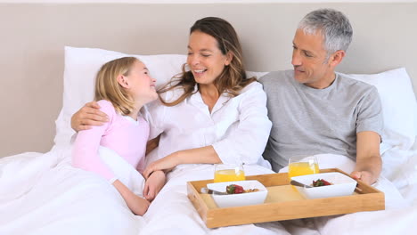 familia sonriente sentada en una cama