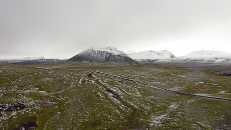 Luftbild:-Seitenverfolgung-Eines-Autos,-Das-Auf-Einer-Teilweise-Schneebedeckten-Bergstraße-Im-Isländischen-Hochland-Fährt