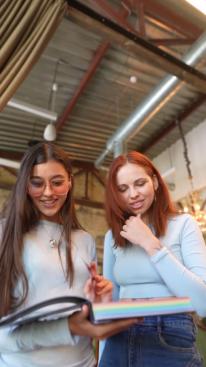 dos amigas leyendo un libro en un café
