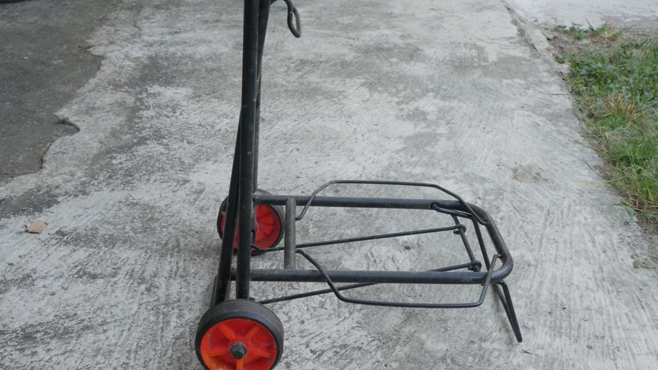 Prázdný vozík na barely s vodou stojící na betonové ploše.