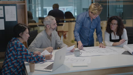 group of senior architects discussing floor plans in the office