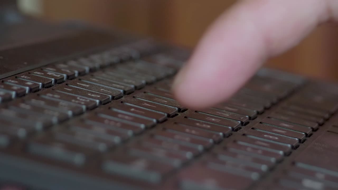 Pressing computer laptop keyboard button with one finger, remote worker