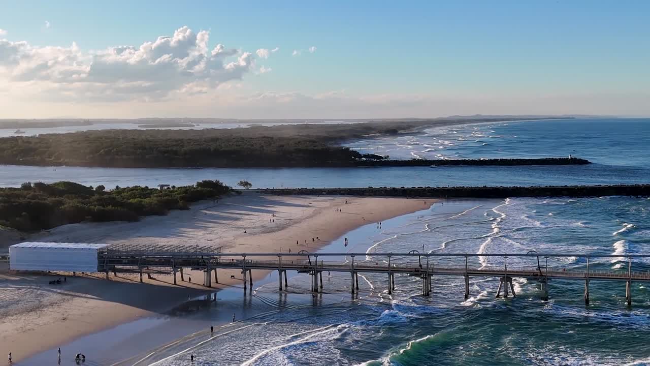 Riprese con drone catturano un lungo molo costiero che si estende nell'oceano durante l'ora d'oro