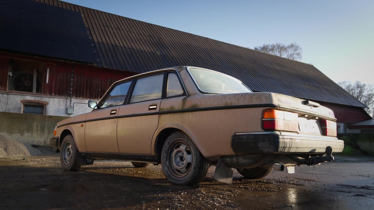 Un coche clásico descuidado se encuentra fuera de un edificio de granja rural antes de ser lavado y restaurado. Ideal para hallazgos de granero, automoción vintage, restauración y contenido campestre.