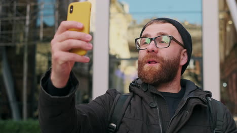 bearded man making a video call on his smartphone in the city