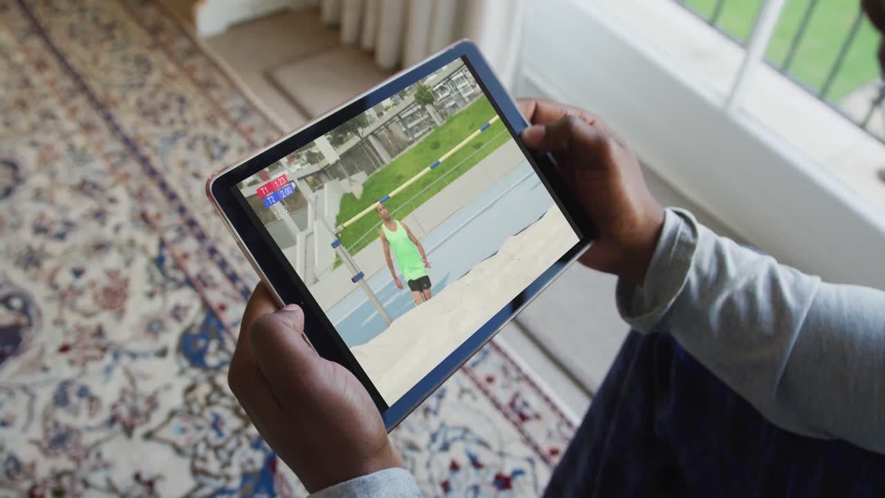 compuesto de un hombre sentado en casa viendo atletismo salto de altura evento en la tableta