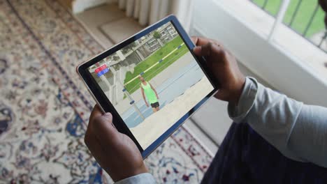 compuesto de un hombre sentado en casa viendo atletismo salto de altura evento en la tableta