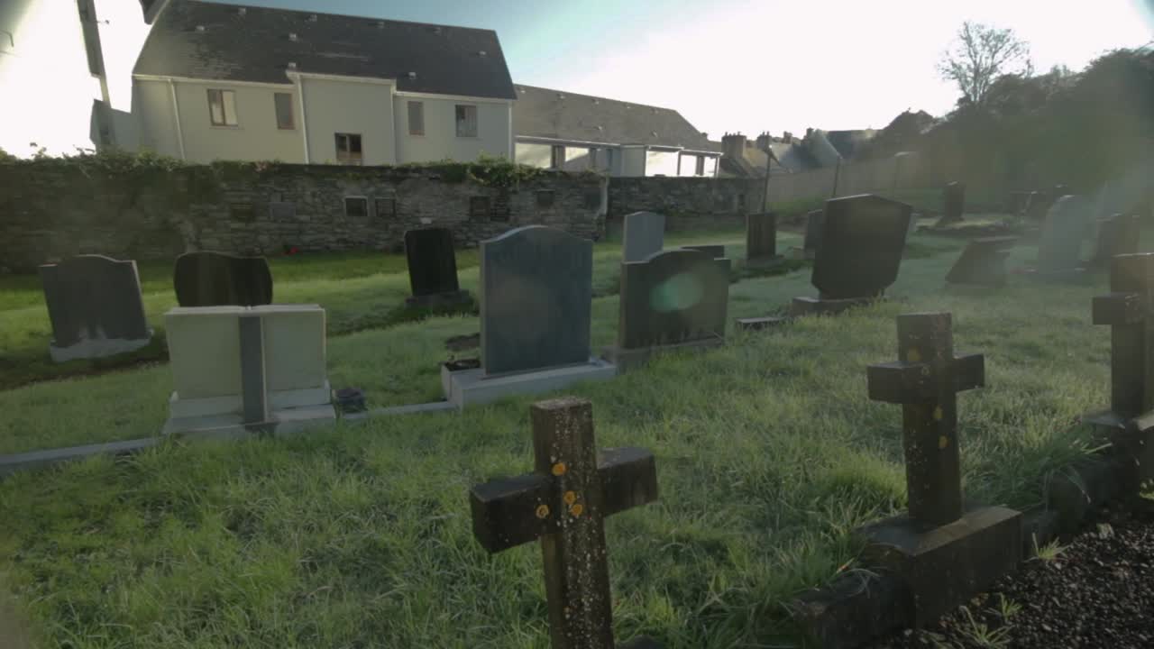 Slow pan through abandoned grave yard in Ireland with sun flar coming through clouds