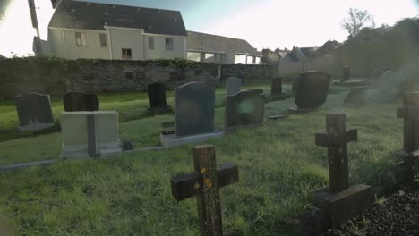 slow pan through abandoned grave yard in ireland with sun flar coming through clouds