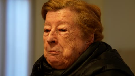 elderly woman enjoying chips at home in the evening light, closeup shot