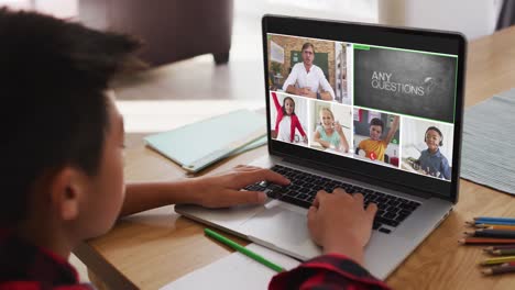 Schoolboy-using-laptop-for-online-lesson-at-home,-with-diverse-teacher-and-class-on-screen