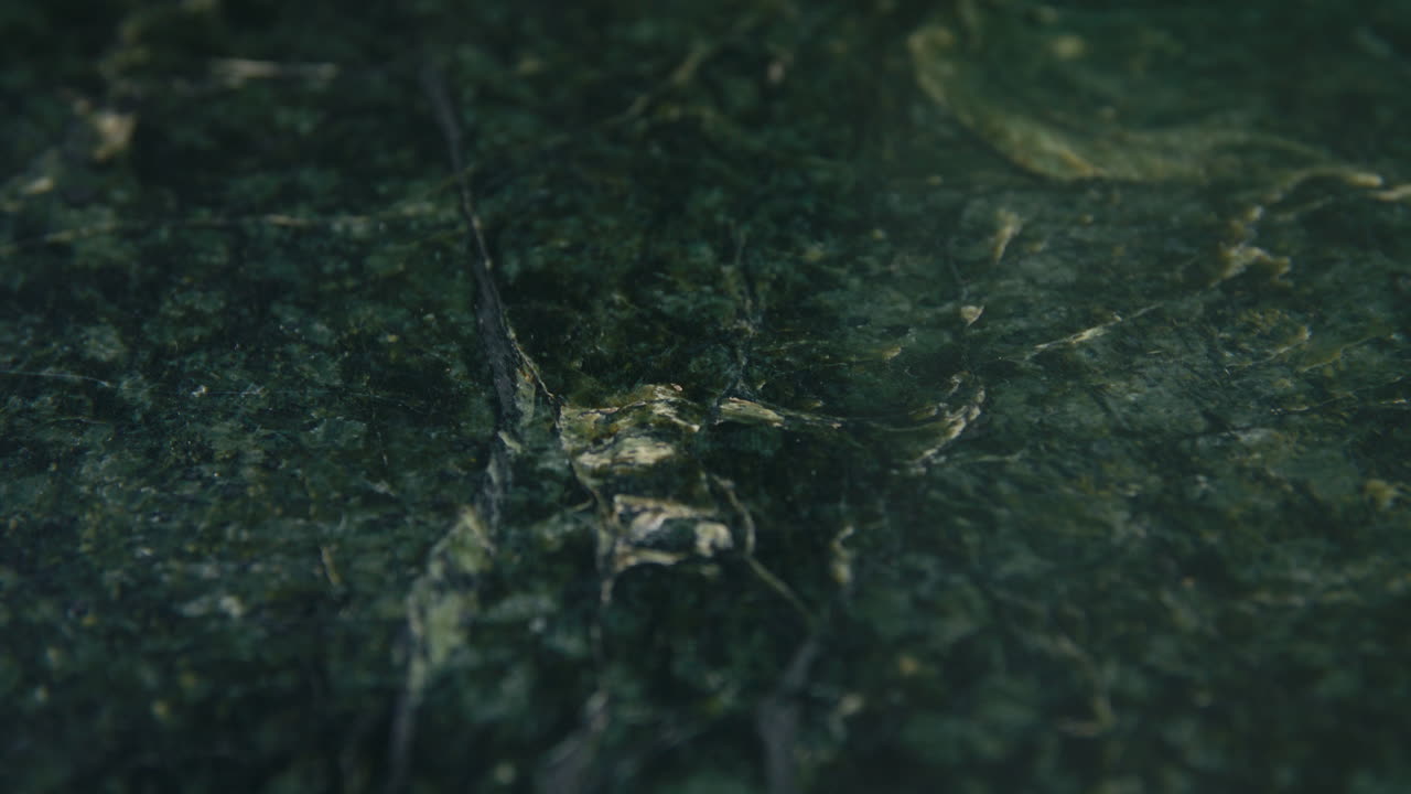 A soft, cinematic glide over a deep green marble surface reveals a gold bitcoin, highlighting the contrast between digital innovation and timeless material beauty